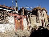 
People On The Roofs Of Houses In Nar Village Stacked With Hay And Cows Down Below
